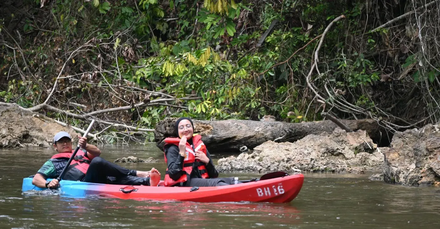 Dua orang berkayak di sungai berbatu